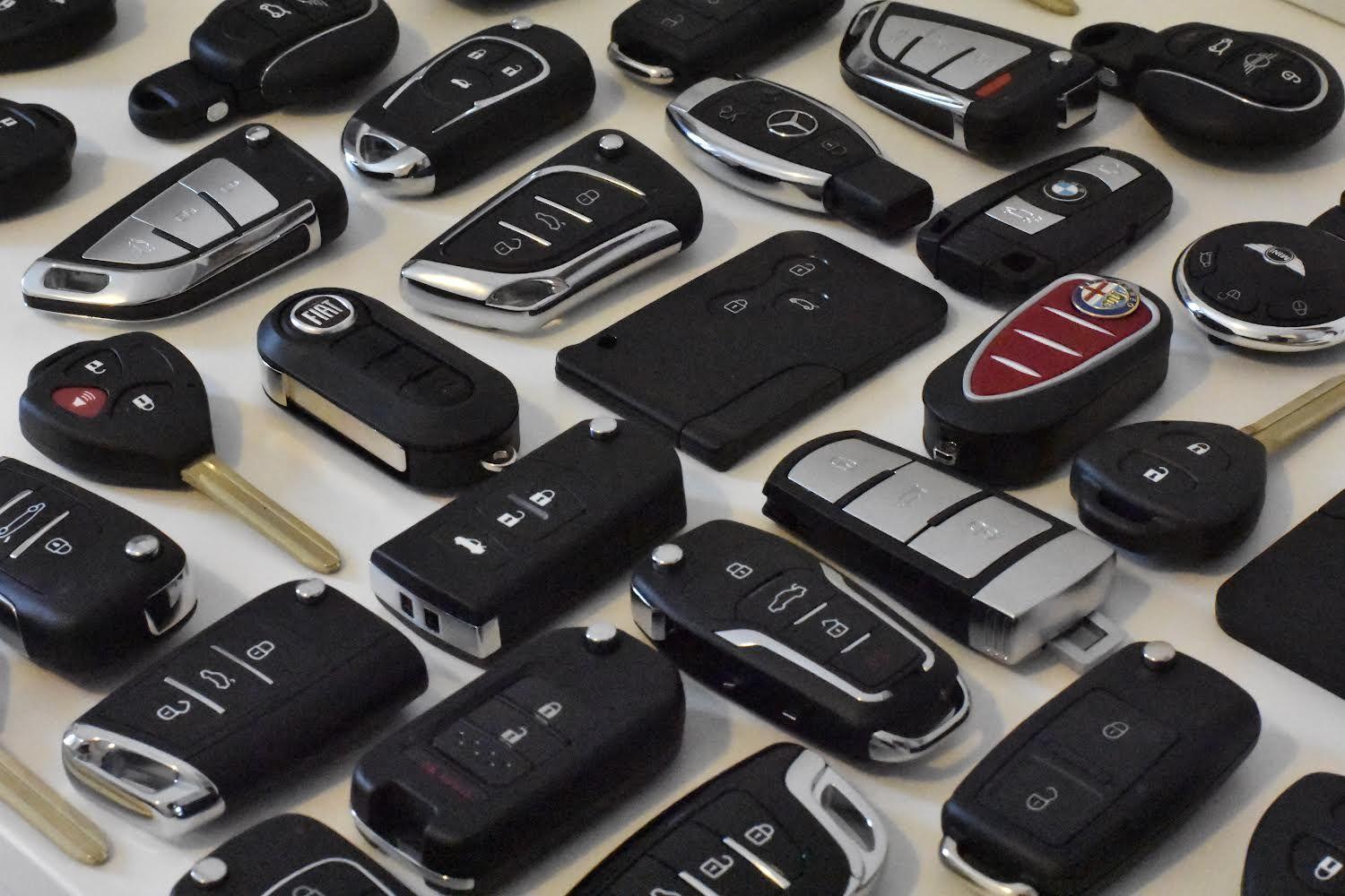 Collection of various car key fobs and remote controls displayed on a flat surface.